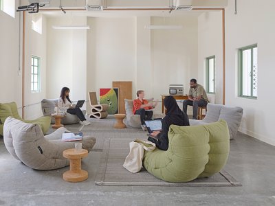 Indoor lounge area with large bean-bag style seating with people relaxing and talking.