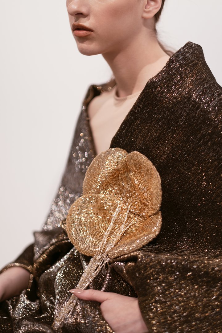 Close-up of a sparkling brown dress with a large flower decoration in gold