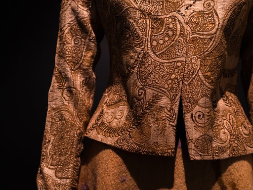 An intricately designed brown blouse and skirt on a mannequin