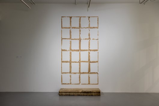 Empty frames in a large column against a white wall.