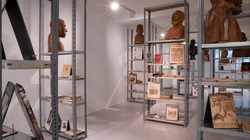 Multiple rust-coloured busts and printed publications are seen displayed on metal cases.