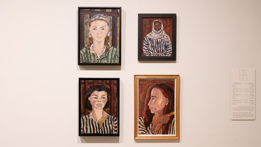 Four paintings, women's portraits, hang in a rectangle formation against a white wall.