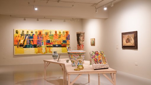 Multiple artworks, including paintings and ceramics, are shown displayed in one white gallery space.