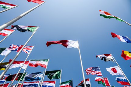 A worm's-eye view of multiple flags on high poles.