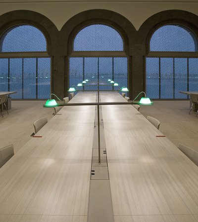 Interior of the MIA library showing long tables and lit desk lamps at night