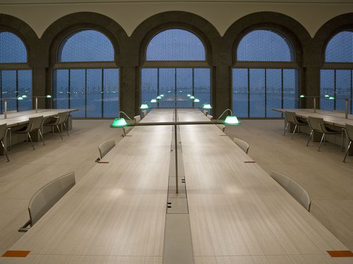 Interior of the MIA library showing long tables and lit desk lamps at night