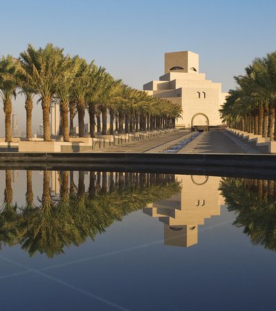 Asymmetrical view of the MIA with stairs, palm trees and water fountain leading up to the entrance