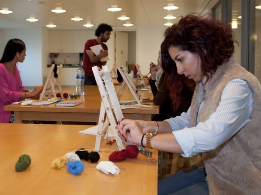 A lady participates in an workshop using string of various colours to create her art work