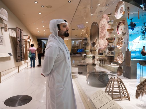 Qatari man viewing the National Museum of Qatar gallery while listening to an audio guide tour of the collection
