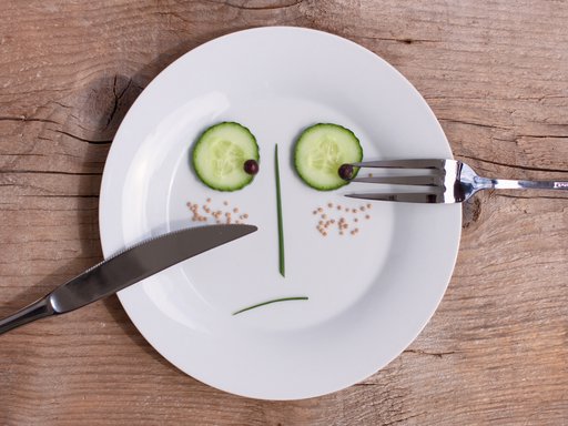 A sad face created by vegetables, sitting on top of a white plate