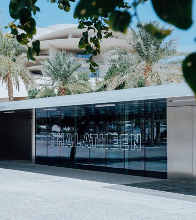 An exterior view of Thalatheen Cafe with the National Museum of Qatar in the background