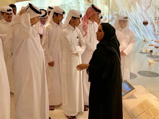 A woman tour guide explaining the National Museum of Qatar collection to students