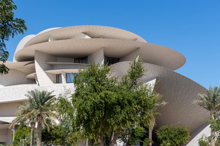 مجموعة من الأشجار والنباتات ويظهر متحف قطر الوطني في الخلفية