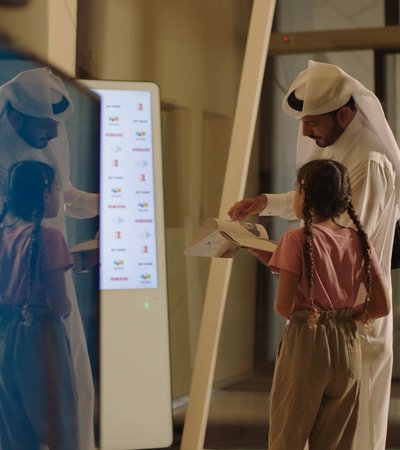Qatari man and his daughter browsing the catalogue of the National Museum of Qatar