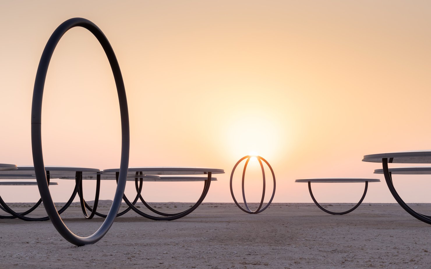 Circular shelters and rings placed in a desert landscape