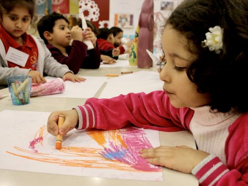مجموعة من الأطفال في ورشة رسم حيث أقلام تلوين والأوراق متناثرة على الطاولة