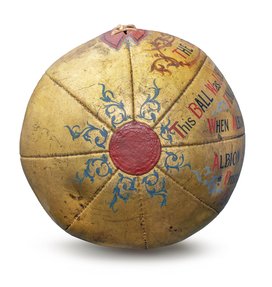 A golden coloured football with red leather sections and intricate blue designs.