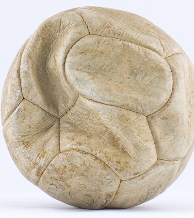 A white football, time-weathered leather, with faint blue writing visible.