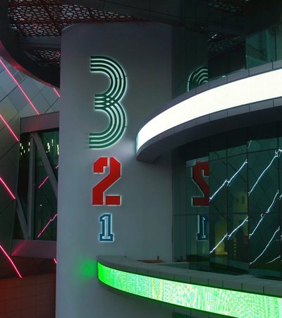 An image of neon lights highlighting the QOSM 3-2-1 signage