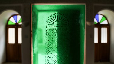Two arched doorways are separated by a green central image of a carved window covering.
