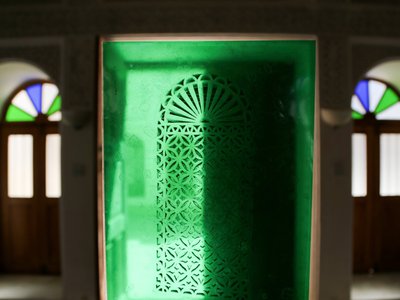 Two arched doorways are separated by a green central image of a carved window covering.