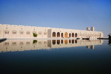 منظر خارجي لمتحف الشيخ فيصل بن قاسم خلال النهار، يظهر انعكاس المبنى في الماء