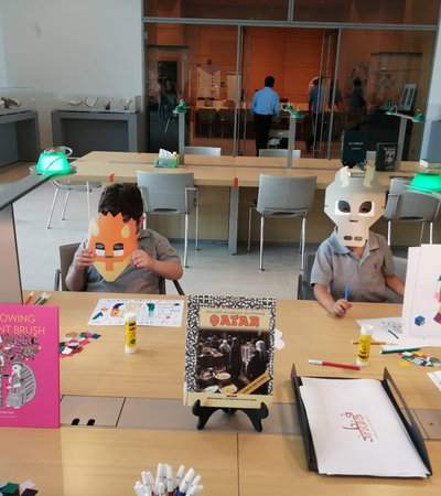 Children making masks out of chart-paper and holding it up against their face
