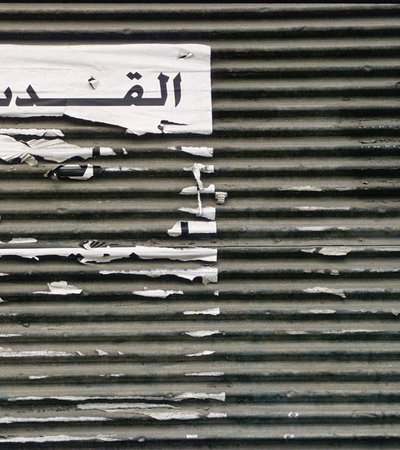 Picture of shredded paper on a textured background with the word Al Quds in Arabic
